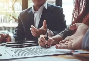 Two professionals discussing and signing a document at a table.